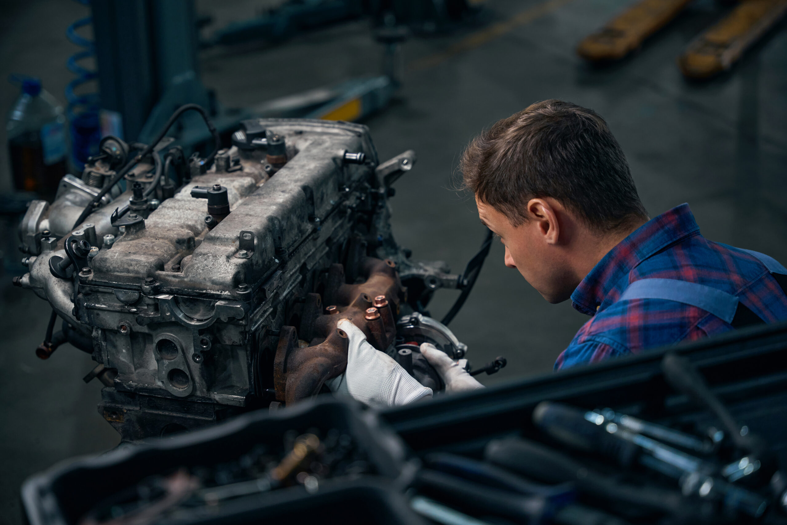 Man installing exhaust manifold on machine engine